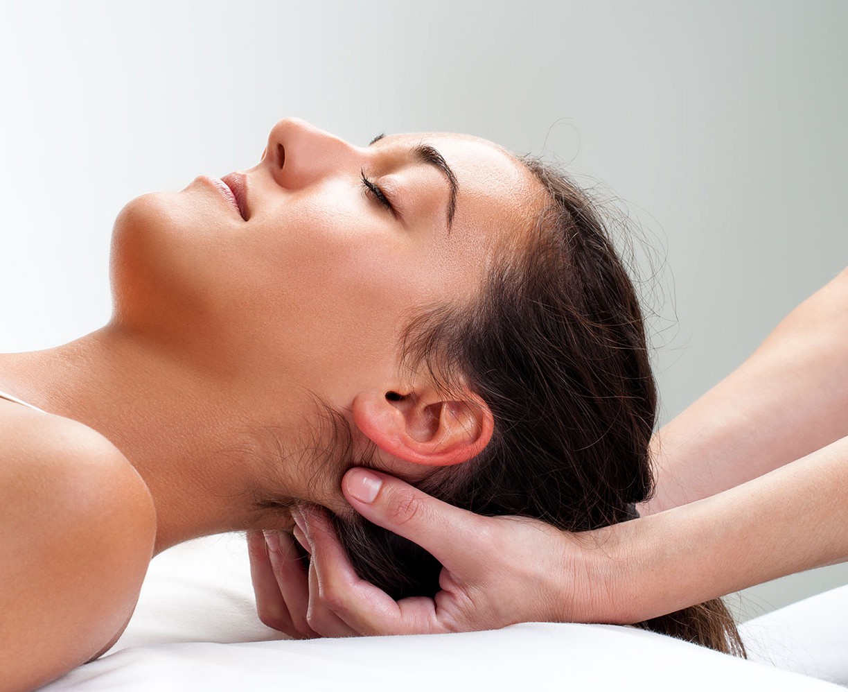 Close up of  chiropractor pressing back of womans head. Therapist doing healing massage with fingers at back of neck.